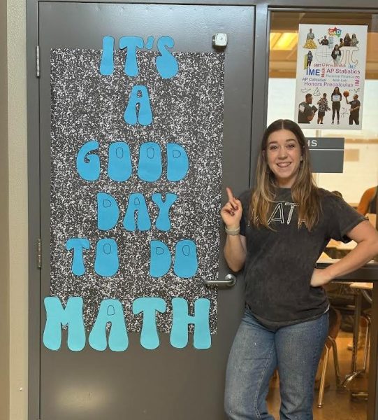 Mrs. Gonzalez standing outside her math room with its amazing poster